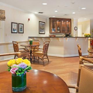 A cozy dining area with wooden tables and chairs, decorated with fresh flowers and featuring a bar counter.