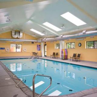 A tranquil indoor swimming pool with skylights and chairs along the sides, providing a relaxing recreational space.