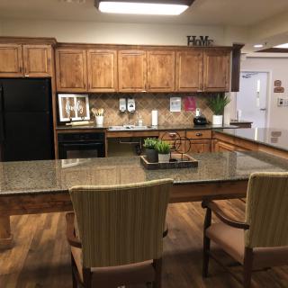 A cozy kitchen with wooden cabinets and a granite-topped island.