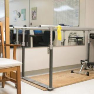 A physical therapy clinic featuring parallel bars and exercise equipment.