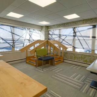A modern office space featuring large windows, contemporary furniture, and ample natural light.