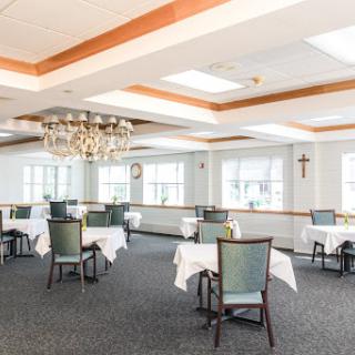 A well-lit dining area featuring elegantly set tables and a decorative chandelier.