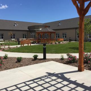 A beautifully landscaped courtyard with a central gazebo and surrounding building on a sunny day.