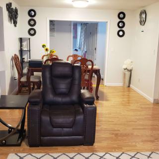 A cozy living room featuring a leather armchair and an adjoining dining area with wooden furniture.