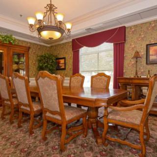 A formal dining room with a wooden table and chairs, adorned with a chandelier and elegant curtains.