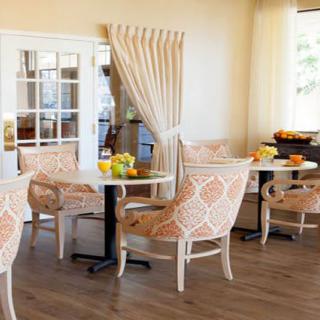 A cozy dining area with stylish chairs and tables, decorated with flowers and bathed in natural light.
