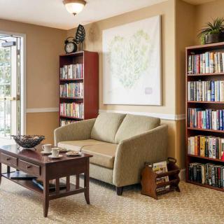 A cozy living room with a comfortable sofa, surrounded by bookshelves filled with books and a wooden coffee table in the center.