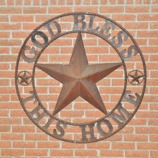 A decorative metal piece displaying the phrase 'God Bless This Home' framed by a star.