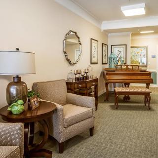 A cozy living room featuring a comfortable sofa, a side table with a lamp, and a piano in the corner.