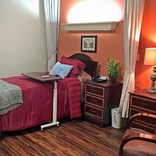 A cozy single-bed hospital room with warm lighting and wooden furniture.