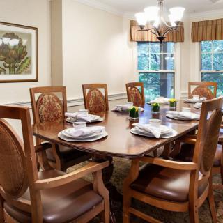 An elegant dining room with a set table and wooden chairs, featuring a window view.