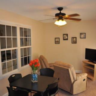 A cozy living room with a dining area, featuring a comfortable sofa, TV, and ceiling fan.