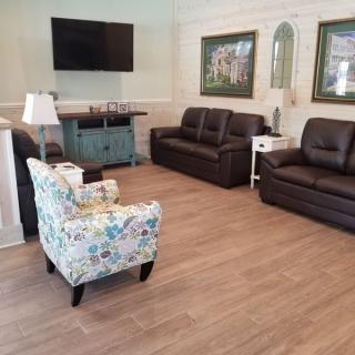 A cozy living room with sofas, a floral armchair, and a television mounted on the wall.