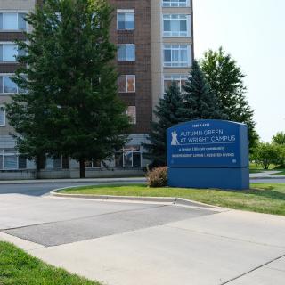 A building with a prominent sign near the entrance, surrounded by trees.