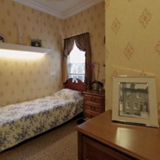 A cozy bedroom with vintage decor, featuring a single bed and wooden furniture.