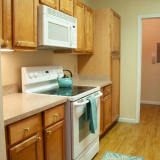 A cozy kitchen with wooden cabinets, a white stove, and a teal teapot.