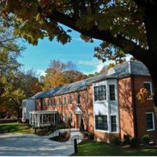 A brick residential building surrounded by trees in autumn.