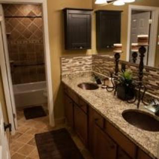 A well-designed bathroom featuring a double sink with granite countertops and decorative tiles.