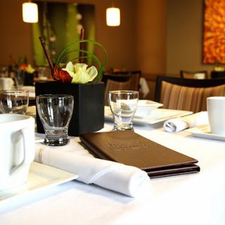 A neatly arranged dining table featuring a menu, glassware, and a decorative centerpiece.