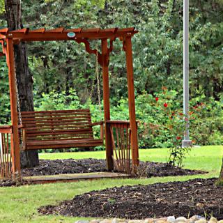 A wooden swing bench in a lush garden setting.