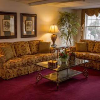 A cozy living room with traditional floral sofas, a glass coffee table, and warm lighting.