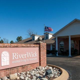 Entrance of RiverWick assisted living facility with a visible sign and flag.