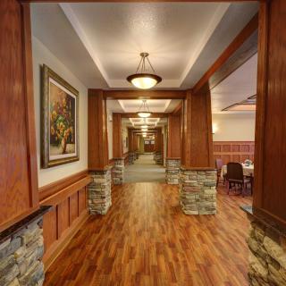 A warmly lit hallway with wooden flooring and stone-accented columns.