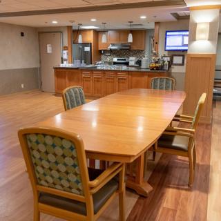 A spacious kitchen and dining area with wooden flooring, featuring a large table and chairs.
