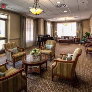 A cozy and inviting lounge area featuring comfortable seating, a piano, and plenty of natural light.