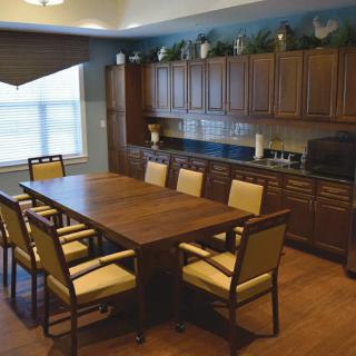A dining room with a wooden table and chairs, surrounded by cabinets.