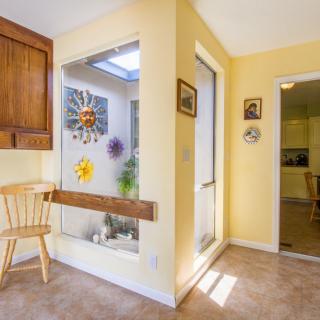 A bright interior with yellow walls, featuring a kitchen area connected to a sunlit room decorated with sun motifs and plants.