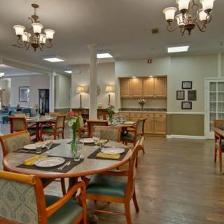 A spacious dining room with neatly arranged tables and chairs, illuminated by elegant chandeliers.