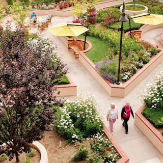 People walking through a beautifully landscaped garden with vibrant plants and flowers.