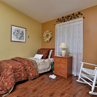 A cozy bedroom with a single bed, nightstand, and rocking chair.