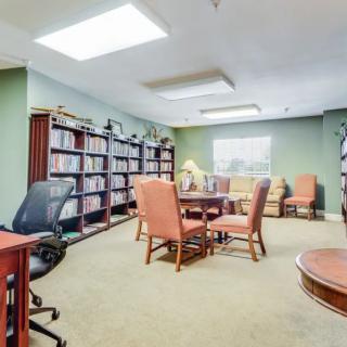 A well-organized office meeting room with bookshelves and a round table surrounded by chairs.