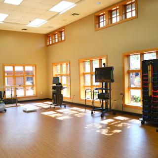 A bright and spacious fitness studio equipped with exercise machines and natural lighting.