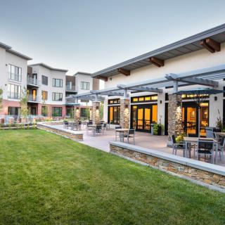 A modern apartment complex with well-maintained landscaping and outdoor seating areas.