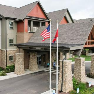 The image shows the entrance of a building with stone pillars and flags displayed in front.