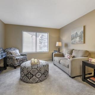 A cozy living room with a sofa, armchair, and patterned coffee table.