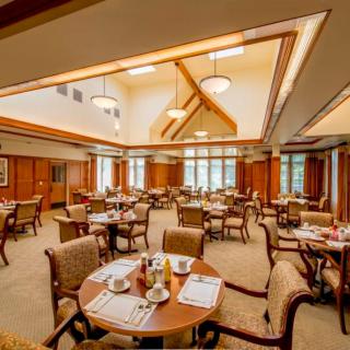 A well-lit dining room with neatly arranged tables and chairs.