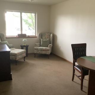 A simple living room with a chair, ottoman, and dining table.