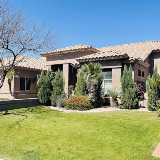 A beautiful residential home with well-maintained landscaping under a clear blue sky.