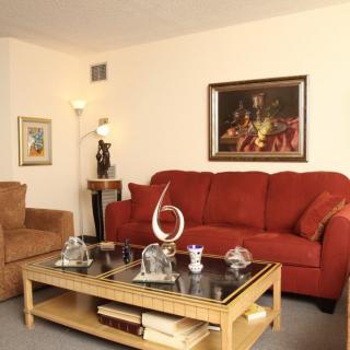 A cozy living room featuring a red sofa, elegant artwork on the wall, and a wooden coffee table with decorative items.