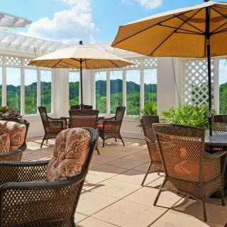 A cozy outdoor patio with cushioned chairs and large umbrellas overlooking a scenic landscape.