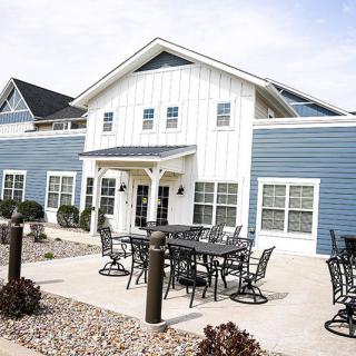 A blue and white residential building with patio furniture arranged in front.