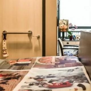 A room with a newspaper spread out on a table and a wheelchair near the door.