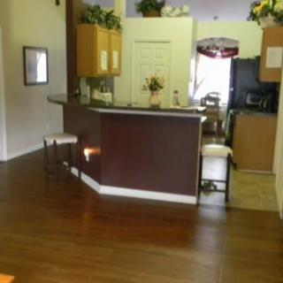 A cozy kitchen with barstools and wooden flooring.