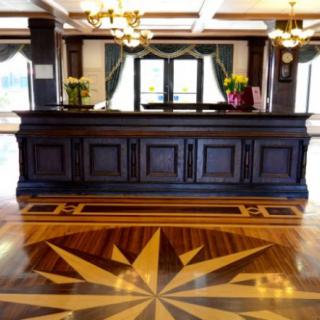 An elegant hotel lobby with a polished wooden reception desk and intricate flooring design.