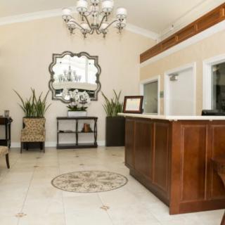 A well-designed reception area featuring a wooden desk, elegant chandelier, and decorative plants.