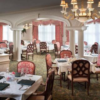 An elegant dining room with neatly arranged tables and ornate chandeliers.
